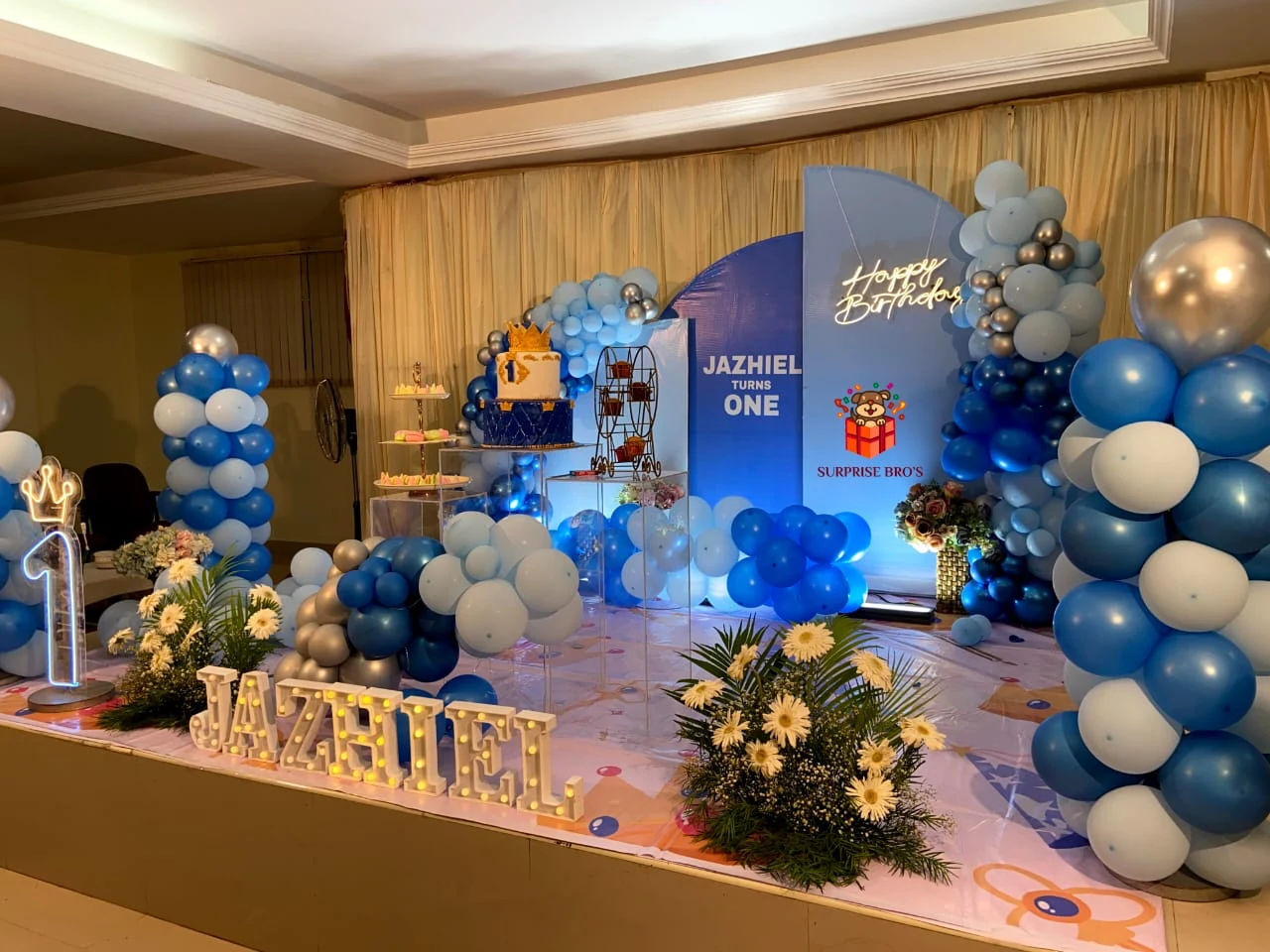 Blue and silver first birthday stage with a crown cake