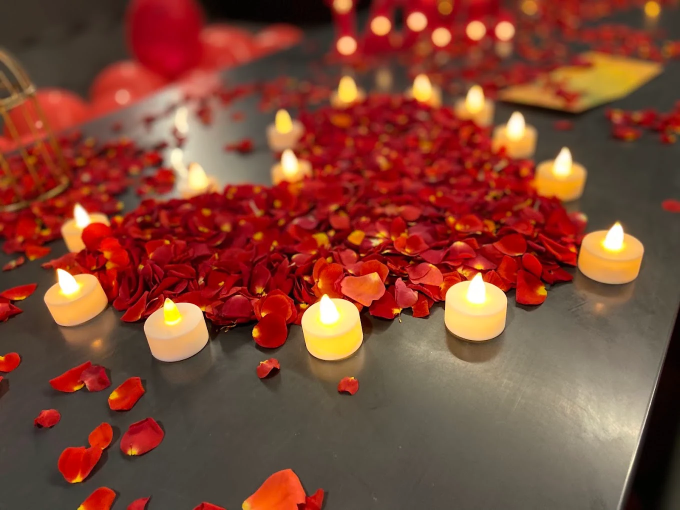 Red rose petals and warm candle lights arranged on a celebration table
