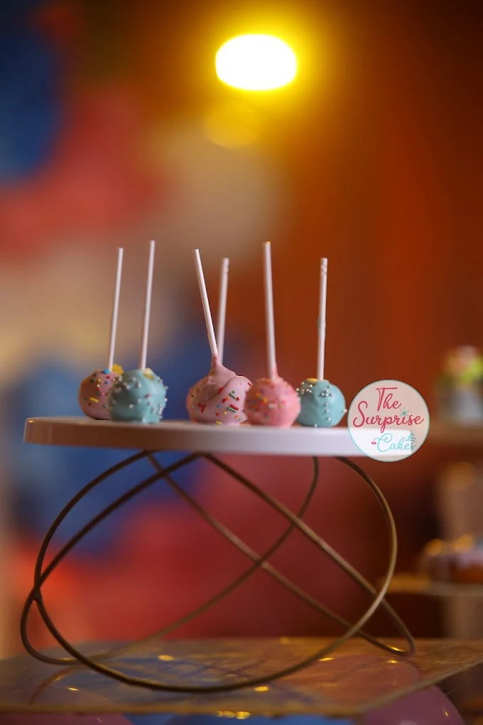 Pink and blue cake pops on a gold display stand