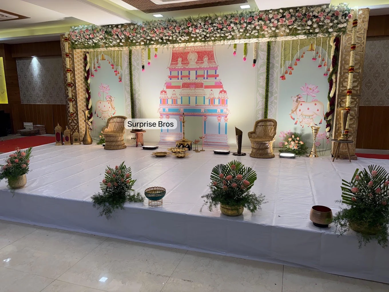 Traditional ceremony stage with a temple illustration and floral canopy