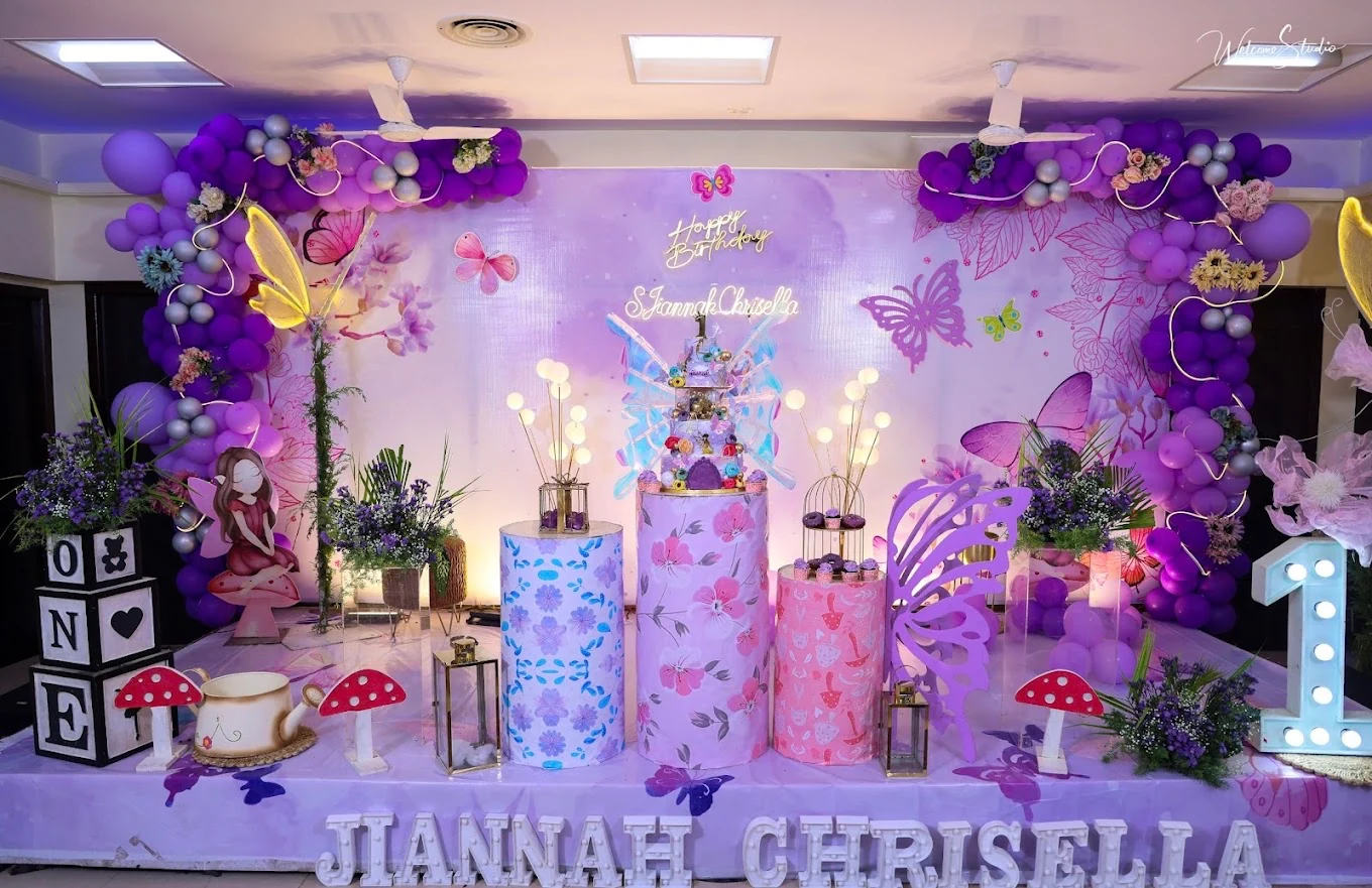 Purple butterfly first birthday stage with floral cake pedestals