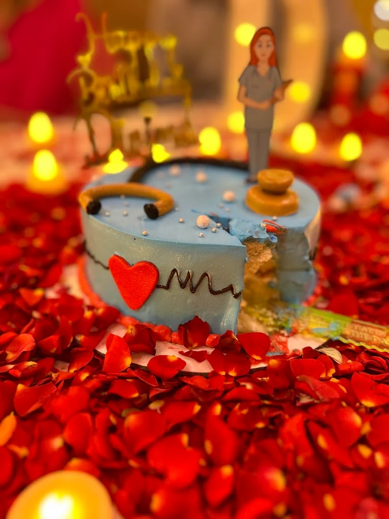 Doctor-themed blue birthday cake surrounded by red rose petals